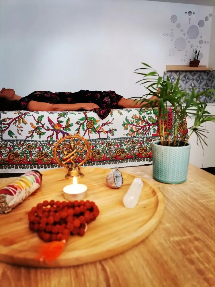 Dans le cabinet : une bougie allumée, des pierres et un chapelet sur un plateau en bois.