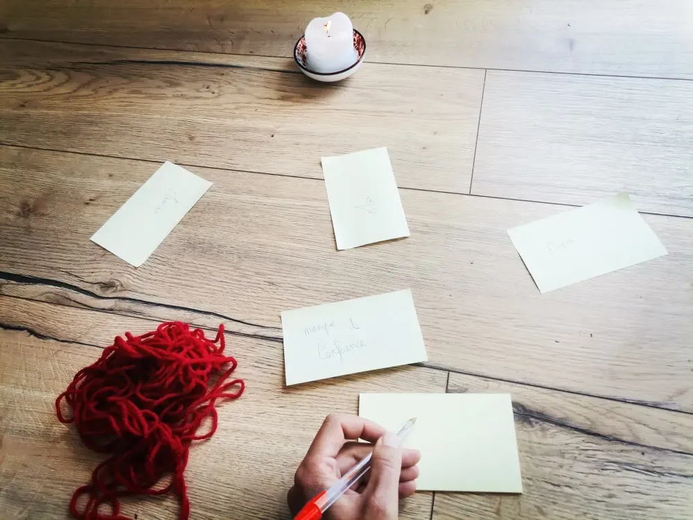 Des post-it et une pelote de fil rouge posés au sol pour une constellation.