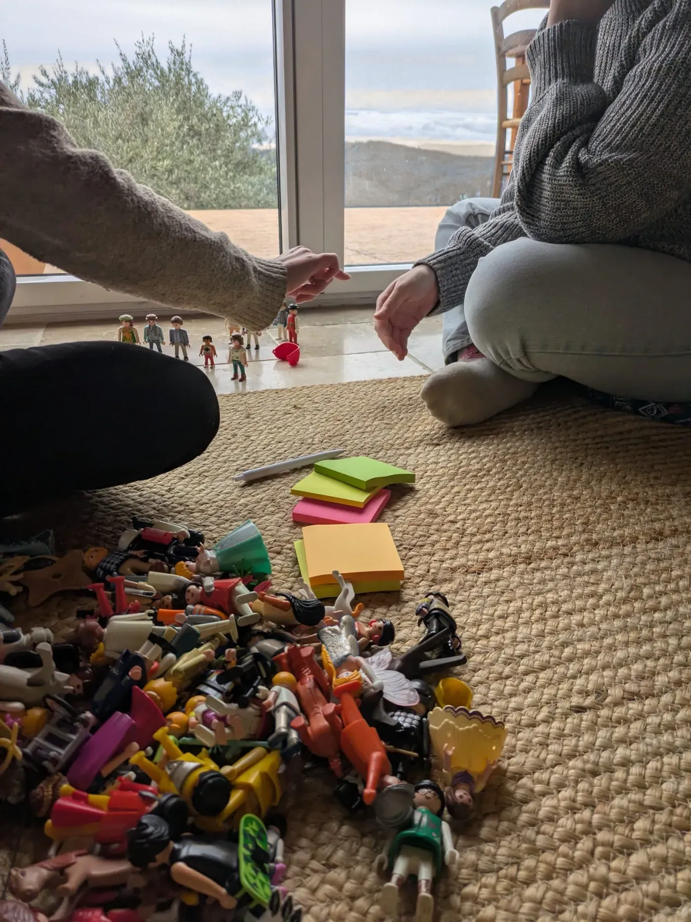 Un tas de figurines Playmobil et des post-it de couleur posés sur un tapis, pendant un exercice.