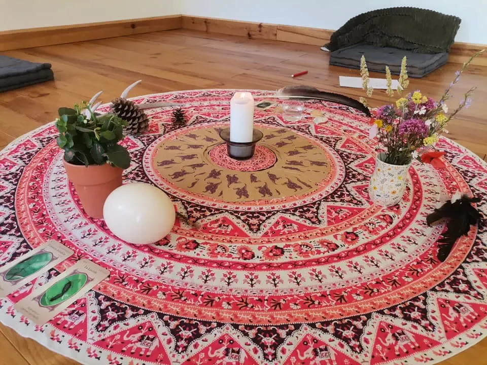 Le centre du cercle : un tissu rouge et ocre, une bougie, des fleurs et des objets choisis.