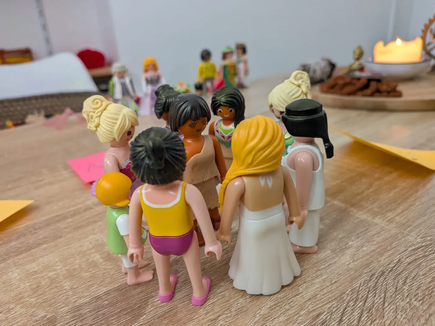 Des figurines Playmobil regroupées sur une table, près d'une bougie.