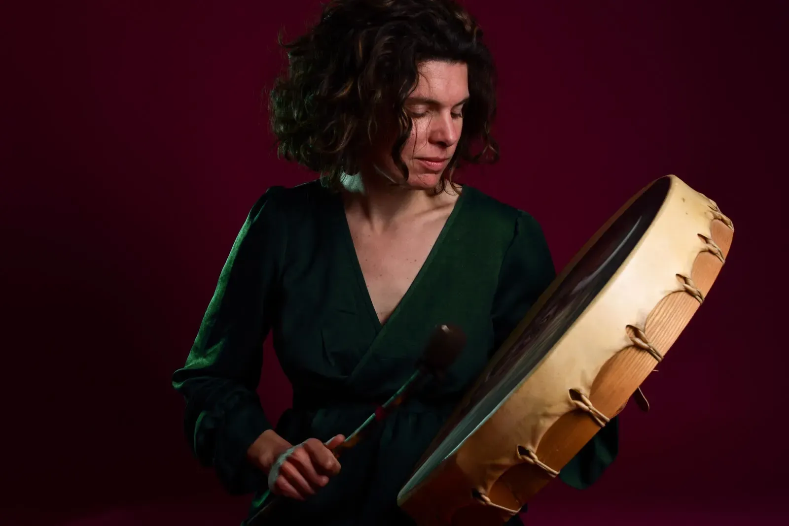 Sandrine en robe verte, tenant son tambour, sur fond grenat.
