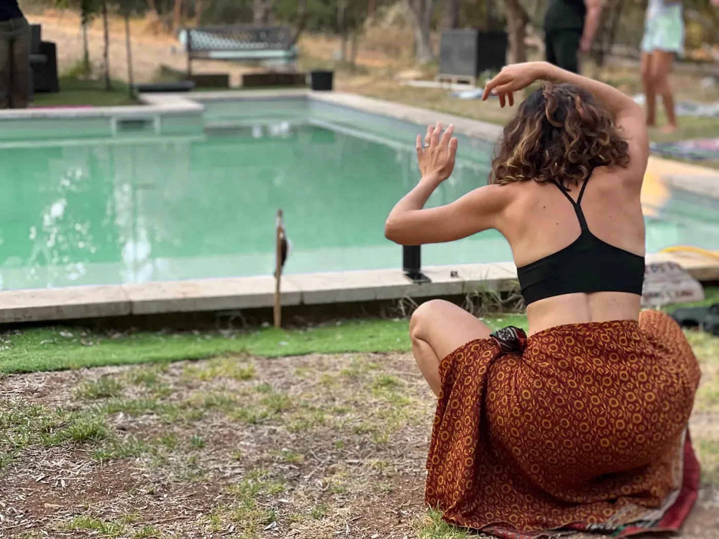 Une femme danse, de dos, au bord d'un bassin, pendant un stage.